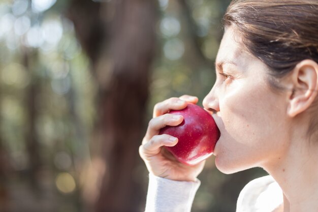 Primer plano de mujer mordiendo una manzana en el parque