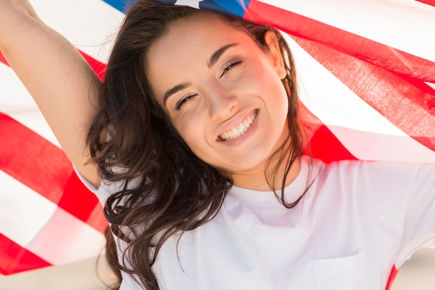 Primer plano mujer morena con gran bandera de Estados Unidos y sonriendo