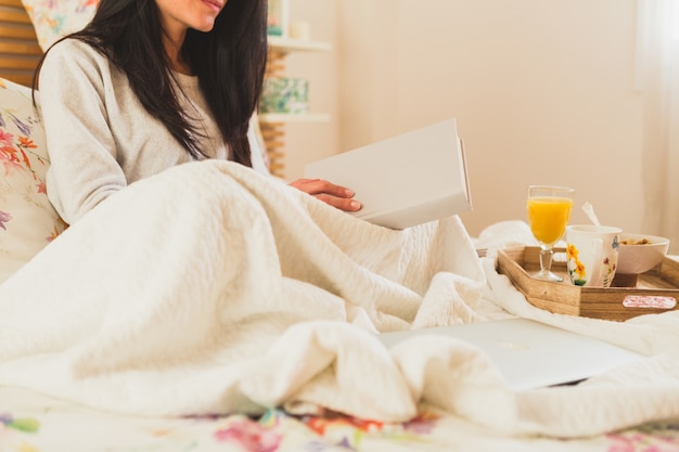 Primer plano de mujer morena leyendo un libro en la cama