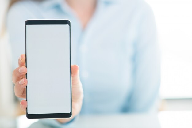 Primer plano de mujer mostrando la pantalla vacía del teléfono inteligente