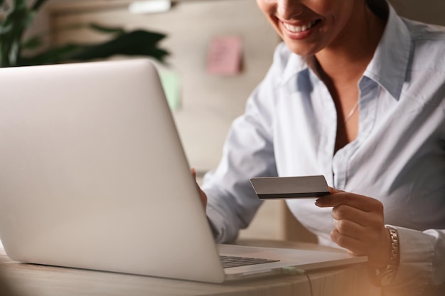 Primer plano de una mujer de negocios comprando en Internet con tarjeta de crédito y una computadora portátil en la oficina