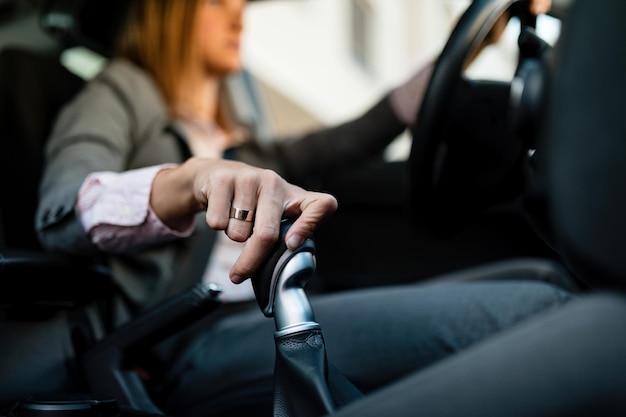 Primer plano de una mujer de negocios conduciendo un automóvil y cambiando la transmisión automática