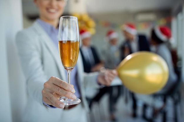 Primer plano de una mujer de negocios con una copa de champán en la fiesta de la oficina de Año Nuevo