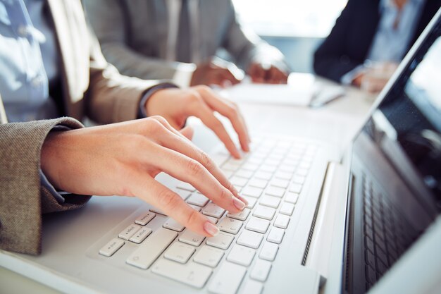 Primer plano de mujer de negocios escribiendo en el teclado de ordenador