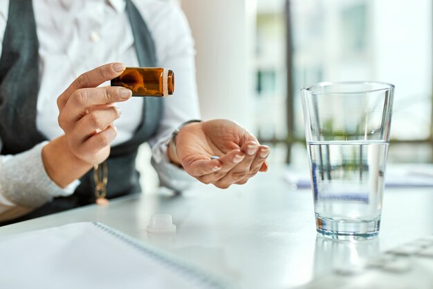 Primer plano de una mujer de negocios irreconocible hablando de pastillas en la oficina