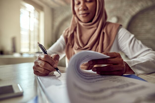 Primer plano de una mujer de negocios islámica negra que firma un contrato en la oficina