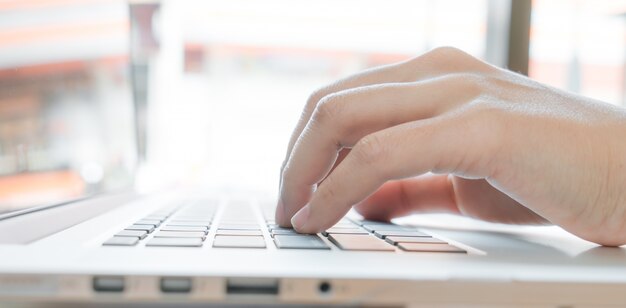 Primer plano de mujer de negocios de la mano escribiendo en el teclado del ordenador portátil