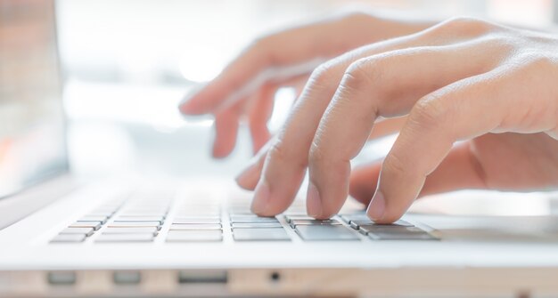 Primer plano de mujer de negocios de la mano escribiendo en el teclado del ordenador portátil