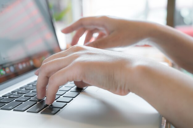 Primer plano de mujer de negocios de la mano escribiendo en el teclado del ordenador portátil