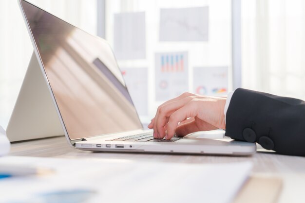 Primer plano de mujer de negocios de la mano escribiendo en el teclado del ordenador portátil