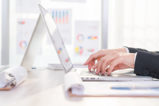 Primer plano de mujer de negocios de la mano escribiendo en el teclado del ordenador portátil