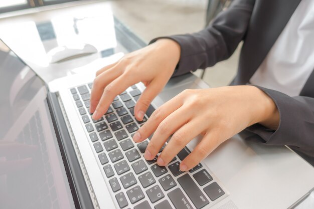 Primer plano de mujer de negocios de la mano escribiendo en el teclado del ordenador portátil.