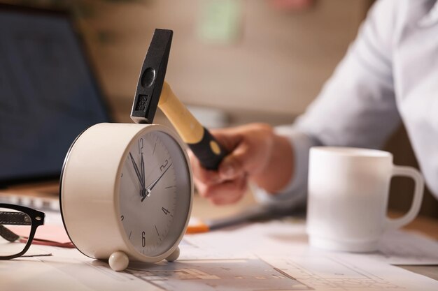 Primer plano de una mujer de negocios que golpea el reloj en su escritorio mientras trabaja en la oficina