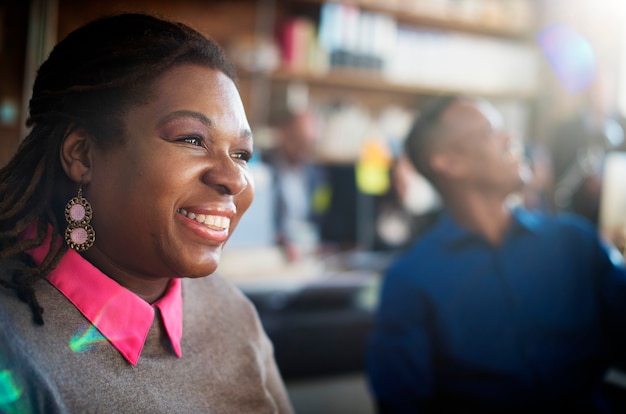 Primer plano de mujer negra sonriendo alegre en el lugar de trabajo