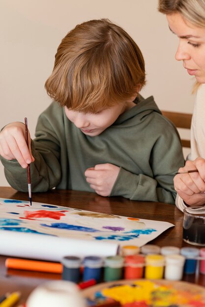 Primer plano mujer y niño pintando sobre papel