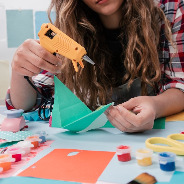 Foto gratuita primer plano de una mujer pegando papel con una pistola de pegamento caliente