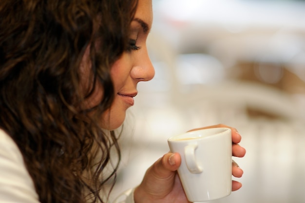 Primer plano de mujer de pelo rizado bebiendo una taza de café