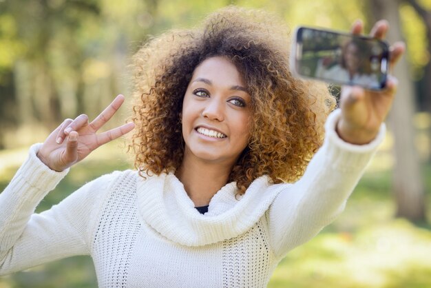 Primer plano de mujer con el pelo rizado haciéndose una autofoto