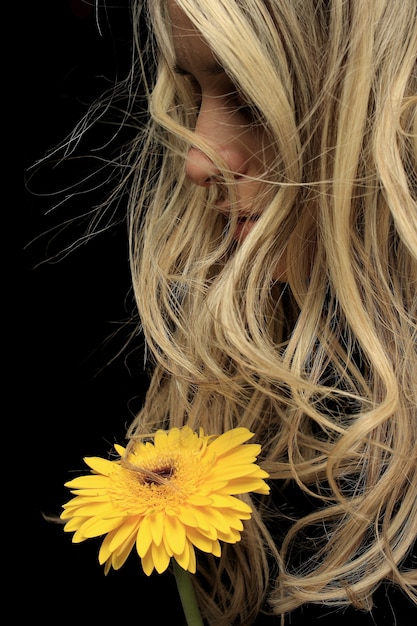 Primer plano de mujer pensativa con una flor amarilla