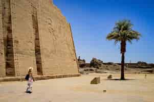 Foto gratuita primer plano de una mujer de pie delante de un templo de medinet habu en egipto