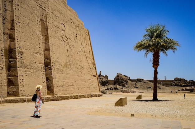 Primer plano de una mujer de pie delante de un templo de Medinet Habu en Egipto