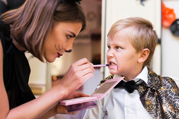 Primer plano mujer pintando cara de niño