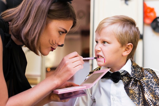 Primer plano mujer pintando cara de niño