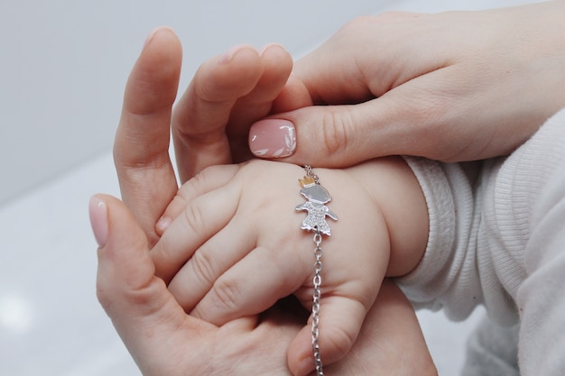 Foto gratuita primer plano de una mujer poniendo una linda pulsera en la mano de su bebé