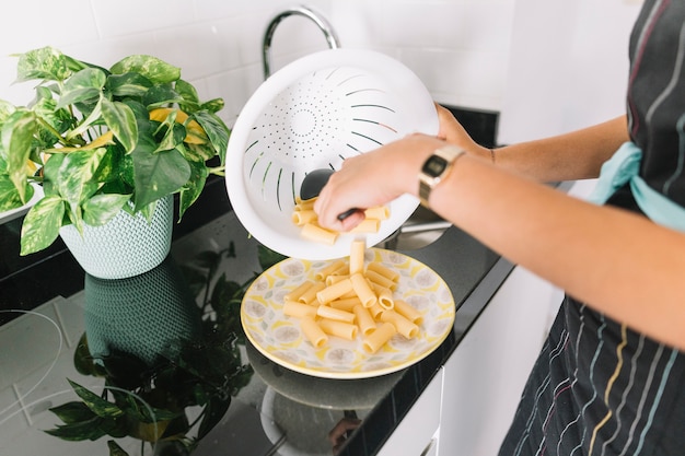 Primer plano de mujer poniendo pasta en el plato