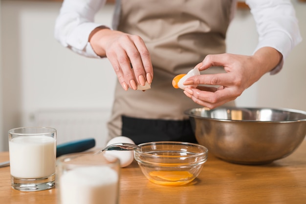 Primer plano de una mujer poniendo yema de huevo en el recipiente de vidrio