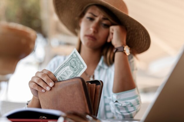 Primer plano de una mujer preocupada que tiene un billete de un dólar en su billetera