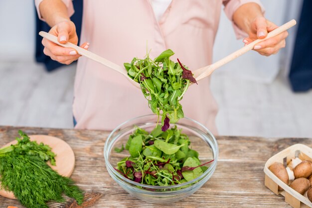 Primer plano de mujer preparando la ensalada de verduras de hoja