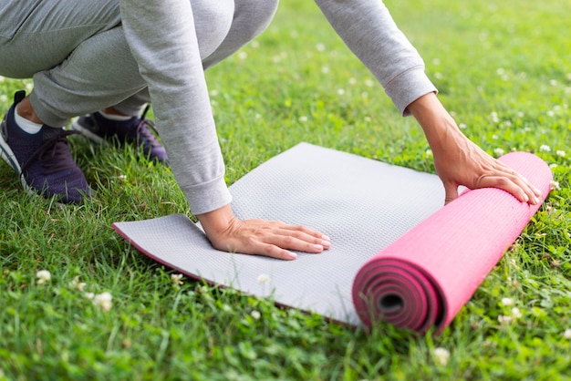 Primer plano mujer preparando estera de yoga