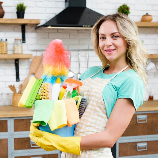 Primer plano de una mujer que sostiene el cubo de herramientas y productos de limpieza