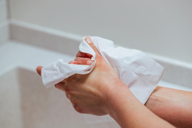 Primer plano de una mujer que usa una toallita antibacteriana y se limpia las manos en el baño
