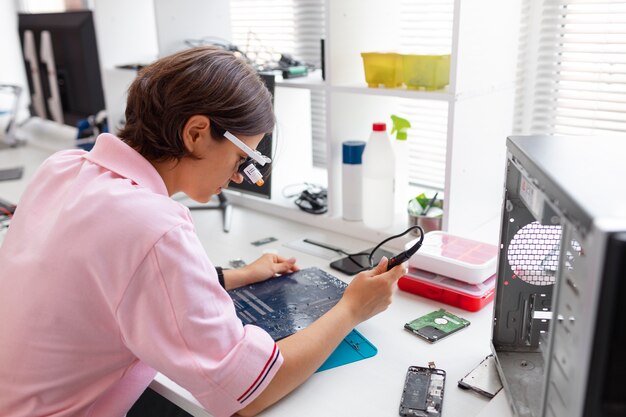 Primer plano de una mujer reparando chips de computadora