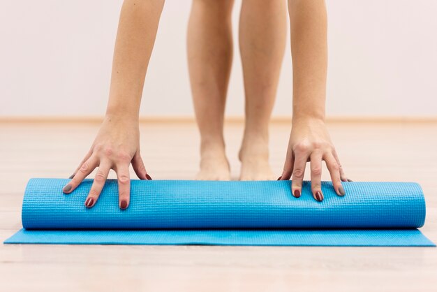 Primer plano mujer rodando estera de fitness después del ejercicio