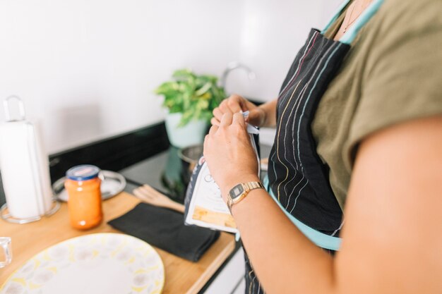 Primer plano de mujer rompiendo el paquete de pasta en la cocina