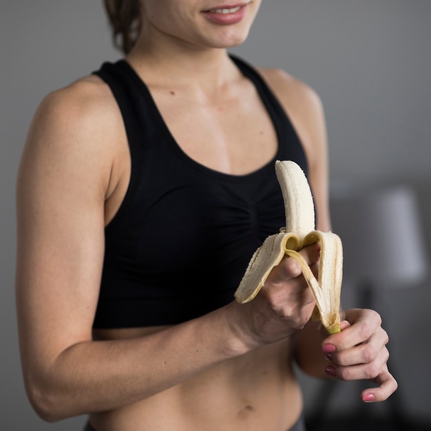 Foto gratuita primer plano de mujer en ropa deportiva pelando plátano