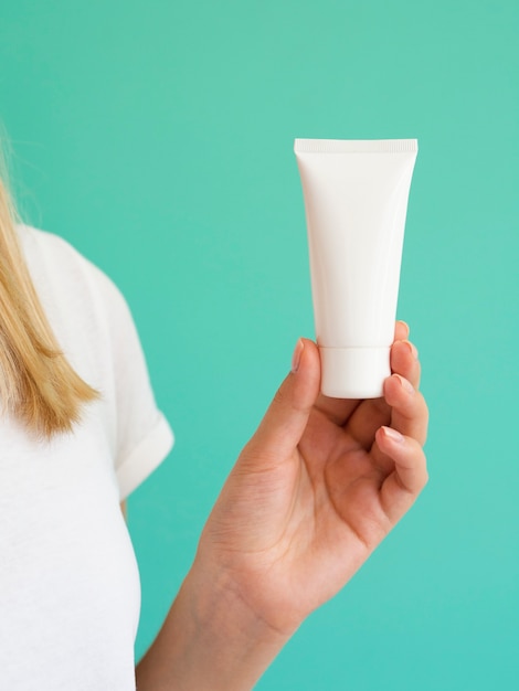 Primer plano de mujer rubia con botella de crema