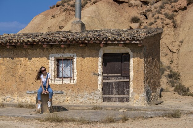 Primer plano de una mujer sentada cerca de una vieja casa trasera