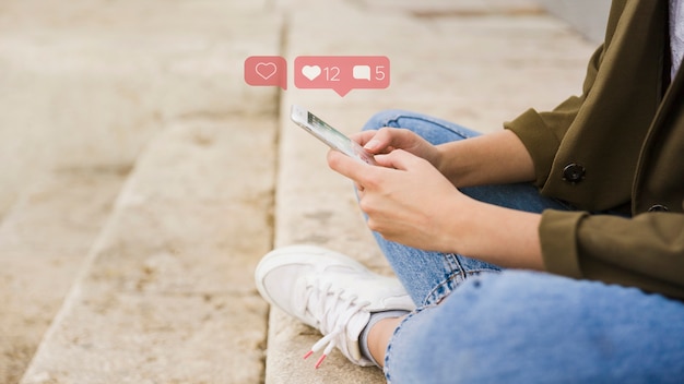 Primer plano de mujer sentada en las escaleras con la aplicación de redes sociales en el móvil