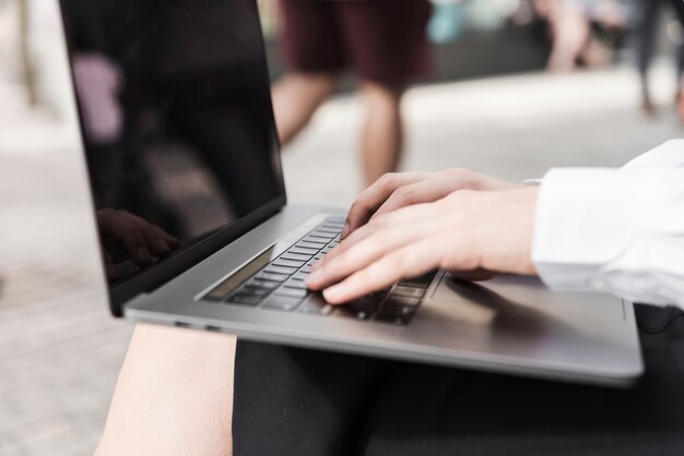 Primer plano mujer sentada trabajando en su computadora portátil