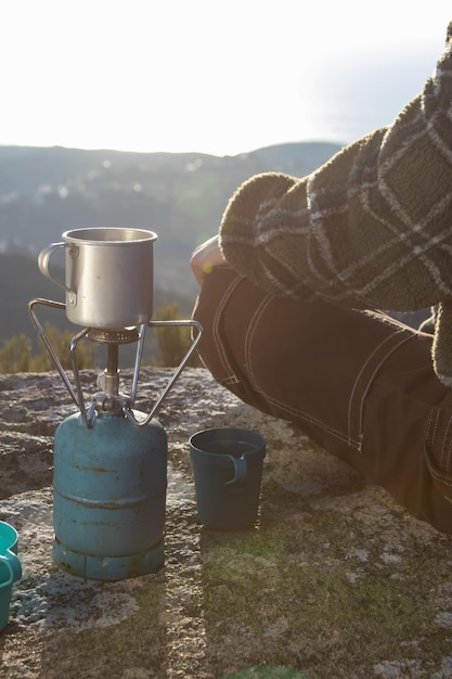 Foto gratuita primer plano, de, mujer se sentar, en, taza, en, portátil, estufa de campamento