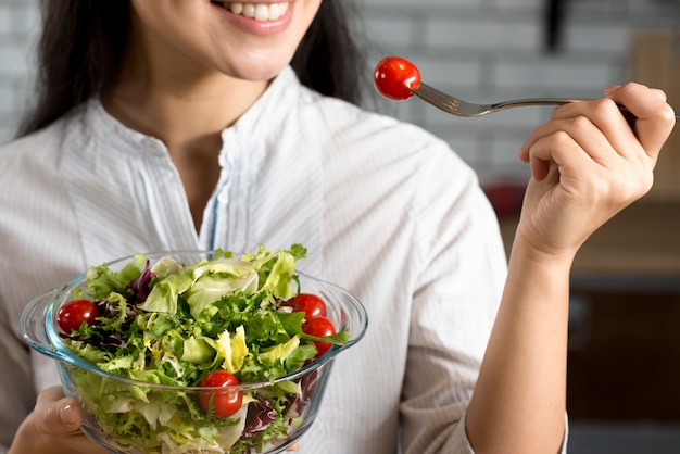 Primer plano de mujer sonriente comiendo ensalada fresca y saludable