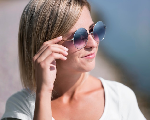 Primer plano de mujer sonriente con gafas de sol