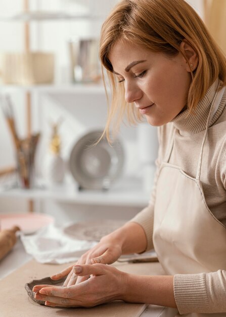 Primer plano mujer sonriente haciendo cerámica en interiores