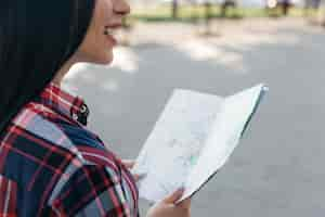 Foto gratuita primer plano de mujer sonriente sosteniendo mapa de pie en la calle