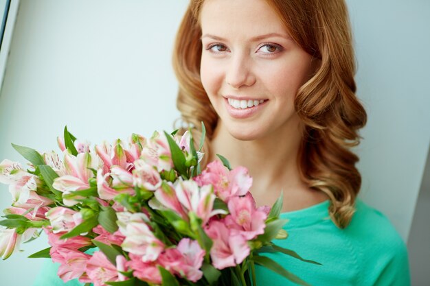 Primer plano de mujer sonriente sosteniendo un ramo de flores