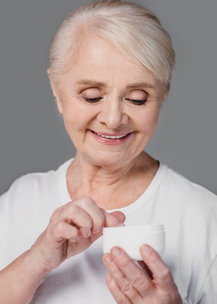 Primer plano mujer sonriente sosteniendo recipiente de crema